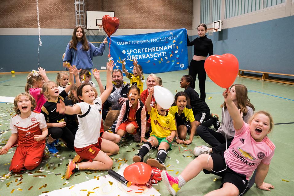 Gruppenszenen mit begeisterten Kindern in Sportkleidung, die Ballons halten und vor einem Danke-Schild feiern.